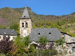 Steinkirche mit Turm und Schieferdach in einem Dorf umgeben von Natur.
