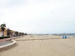 Blick auf den Strand von Puçol mit Sand und Promenade an einem bewölkten Tag.