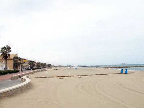 Blick auf den Strand von Puçol mit Sand und Promenade an einem bewölkten Tag.