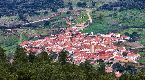 Luftaufnahme eines Ortes mit engen Straßen und roten Dächern in Cáceres.