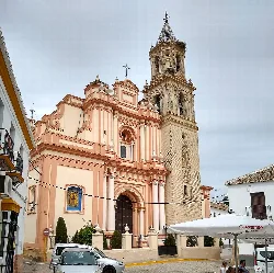 Fachada de iglesia con torre y cielo nublado en Arahal.