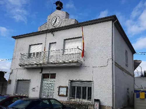 Edificio blanco con reloj y bandera en la fachada.