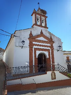 Fachada de una iglesia blanca con campanario y reloj en Villaharta, Córdoba.