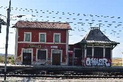 Mingorría station building with graffiti and train tracks in the foreground.
