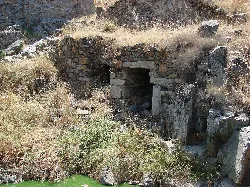 Stone watermill ruins beside a river with dry vegetation.