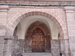 Stone arch and wooden door of a church in Mues.