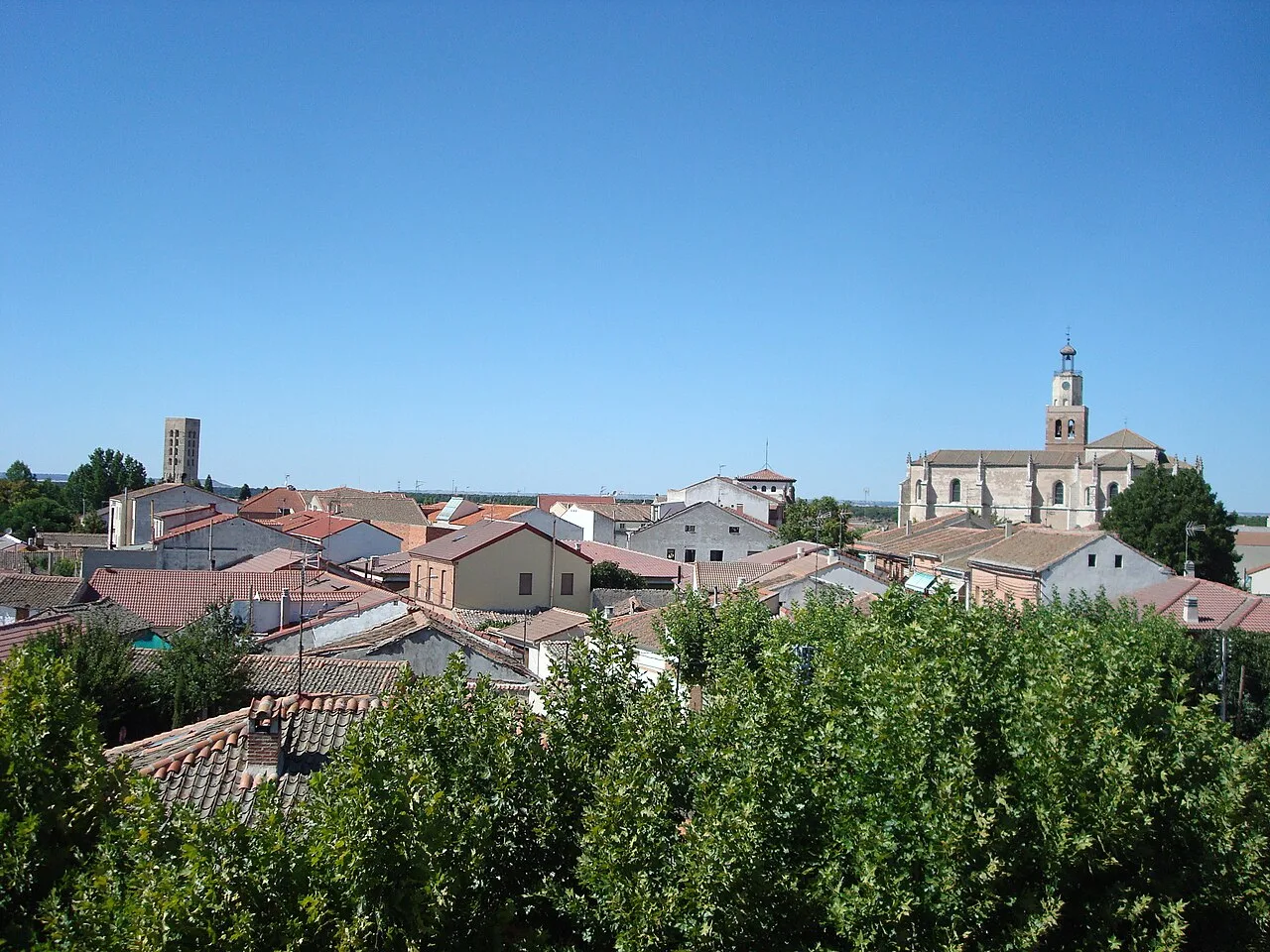 Vista de casas y una iglesia en Coca, Segovia, con cielo azul.