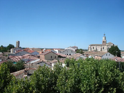 View of houses and a church in Coca, Segovia, with blue sky.