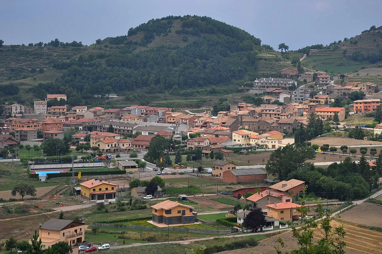 Paisaje de L'Estany con casas y colinas verdes.