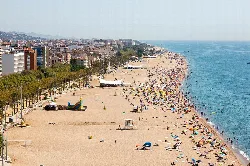 Breiter Strand mit Sonnenschirmen, goldenem Sand und Touristen in Calella.