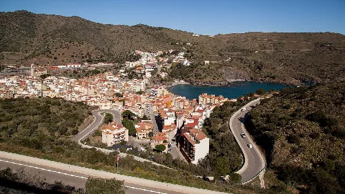 Panoramablick auf Portbou mit Häusern, Bucht und Bergen.