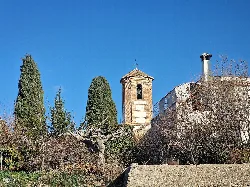 Glockenturm einer Kirche in Gójar mit Bäumen und blauem Himmel.
