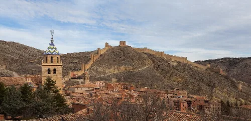Panoramablick auf Albarracín mit Burg auf dem Hügel und Kirchturm im Vordergrund.