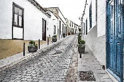 Cobblestone street with white houses and flower pots in San Miguel de Abona.