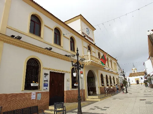 Edificio del ayuntamiento con banderas y farolas en la plaza de San Bartolomé de la Torre.