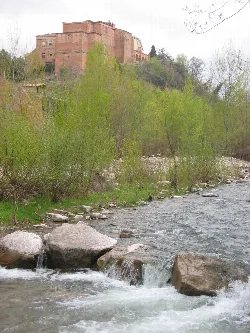 Monastery on a hilltop with river and green trees in foreground