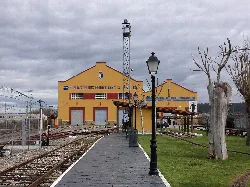Edificio amarillo del museo con vías de tren y señalización.
