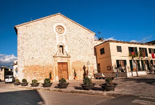 Fachada de una iglesia de piedra con puerta de madera en Costitx, Mallorca.