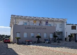 White building with a sign of Casa de Cultura and potted plants at the entrance.