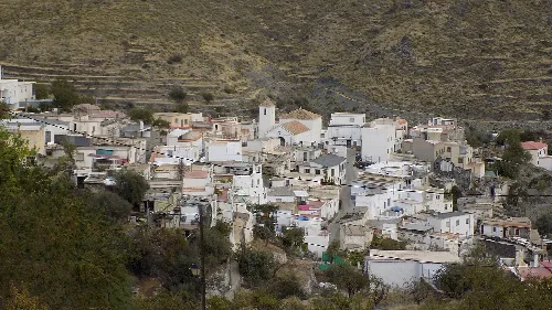 Vista de casas blancas en una colina con montañas al fondo.