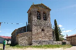 Stone church with a two-story bell tower and a small round door.