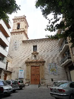Kirchenfassade mit Holztür und Mosaiken an der Wand.