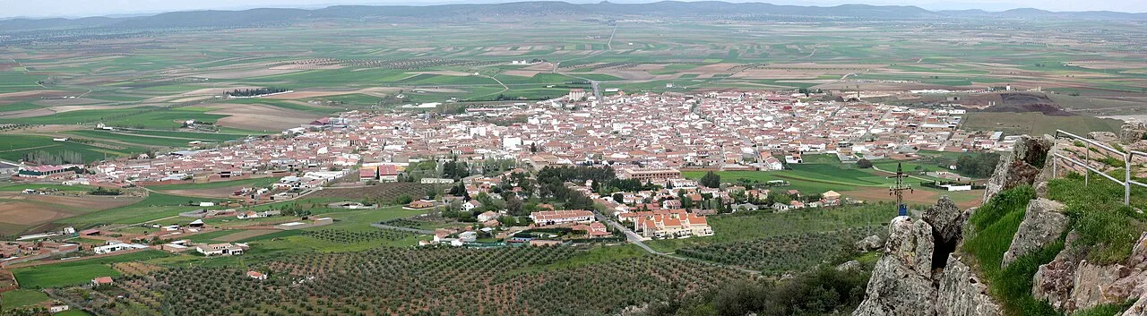 Panoramic view of a town surrounded by farmland and hills.