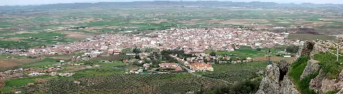 Panoramic view of a town surrounded by farmland and hills.
