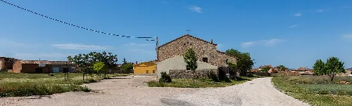 Steinhäuser und Bäume in Villanueva de Gormaz unter blauem Himmel.