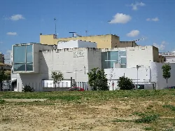 Modern museum building in Santiponce with trees and grass in the foreground.