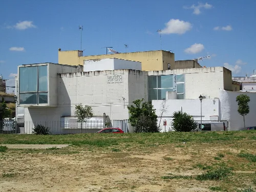 Modernes Museumsgebäude in Santiponce mit Bäumen und Rasen im Vordergrund.