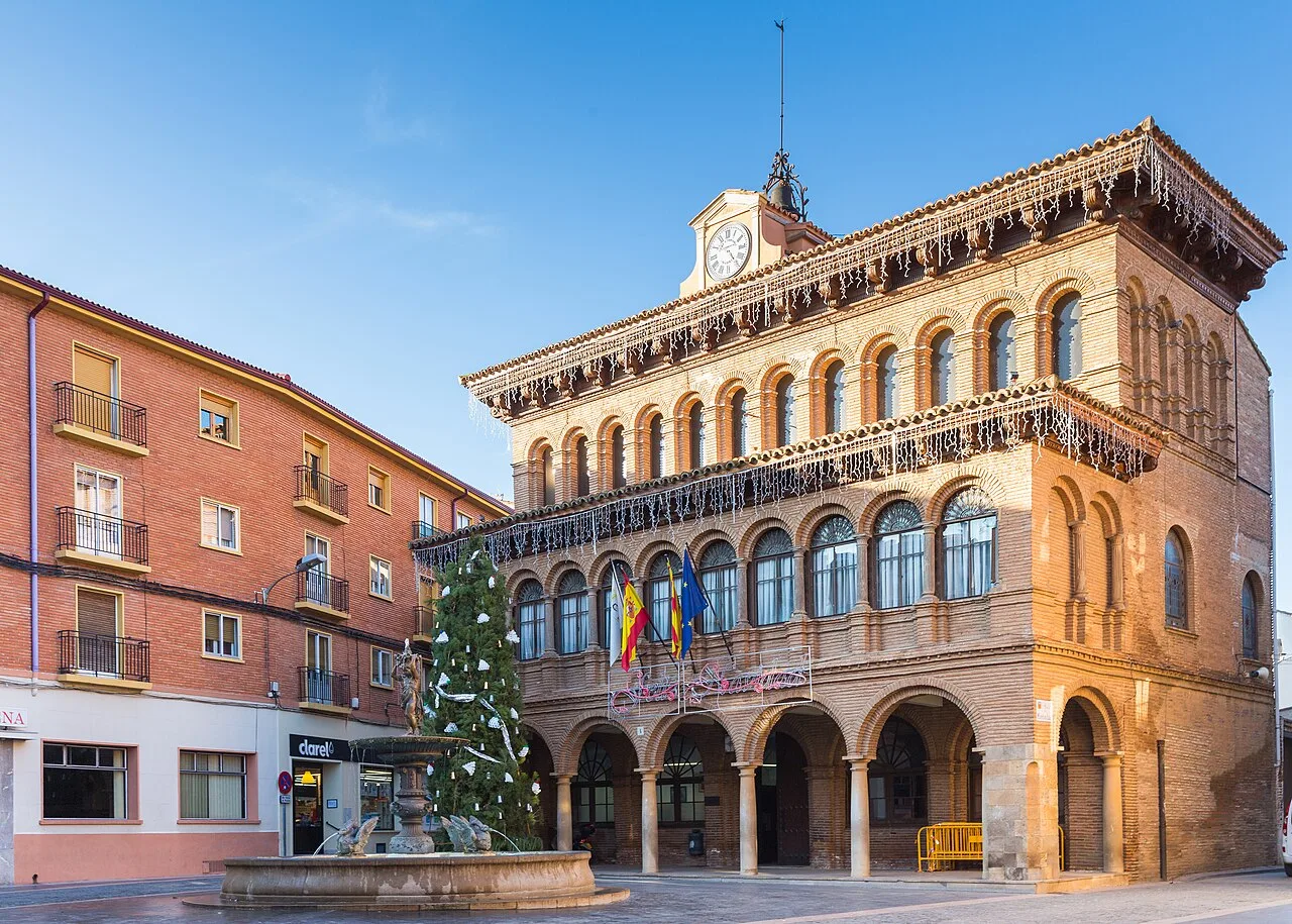 Edificio de ayuntamiento con reloj y banderas en Cariñena.