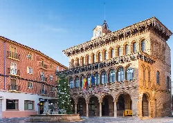 Edificio de ayuntamiento con reloj y banderas en Cariñena.