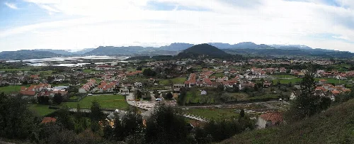 Panoramablick auf Argoños mit Häusern, Feldern und Bergen.