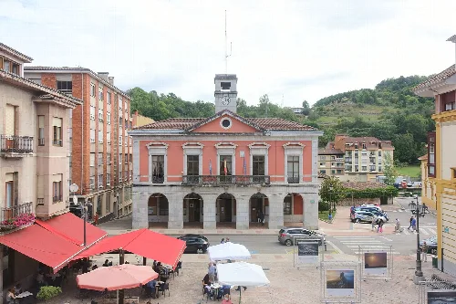 Edificio del ayuntamiento con fachada rosa y arcos en Infiesto.