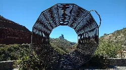 Metallskulptur in kreisförmiger Form mit Landschaft und Roque Bentayga im Hintergrund.