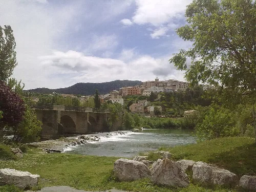 Pueblo de Cáseda junto al río Aragón, con un puente y vegetación.
