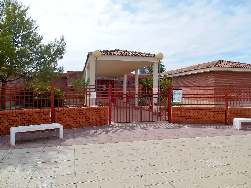 School entrance with red fence and benches in the square.