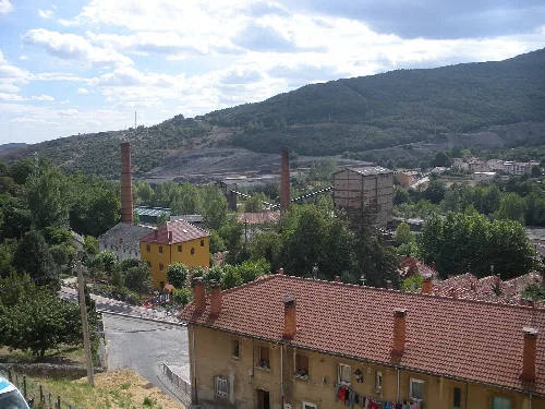 Houses and old mining facilities in Barruelo de Santullán with mountains in the background.