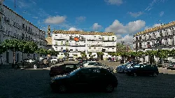 Hauptplatz von Marchena mit weißen Gebäuden, Bäumen und Autos.