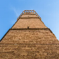 Torre de la iglesia de la Asunción vista desde abajo, con cielo azul.