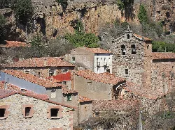 Houses and church in a neighborhood of Anguita, with a cliff in the background.