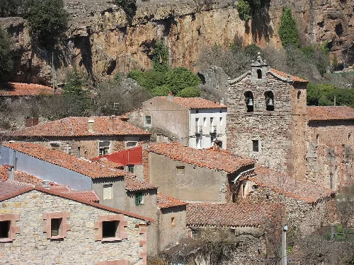 Houses and church in a neighborhood of Anguita, with a cliff in the background.