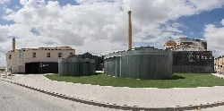 La Conservera building in Ceutí with curved metal shapes and cloudy sky.