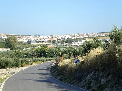 Panoramablick auf Moriles von der Straße mit Vegetation und Geschwindigkeitsbegrenzungsschild.