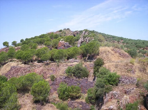 Landschaft mit Bäumen, Felsen und blauem Himmel bei Mina La Jayona, Fuente del Arco.