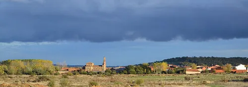 Landschaft mit Kirche und bewölktem Himmel in Quintanilla del Valle, León.