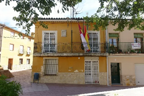 Gelbes Gebäude mit Balkon und Flaggen in Villalba de la Sierra.