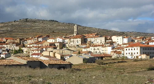 Panoramablick auf eine Stadt mit Häusern und einer Kirche, im Hintergrund Hügel.