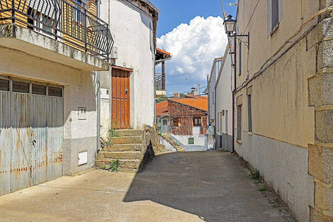 Calle estrecha con casas blancas y un cielo con nubes en Molinillo.
